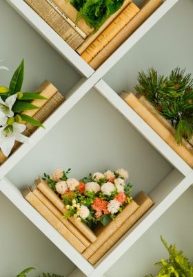 Flowers and plants arranged in boxes on the wall with books